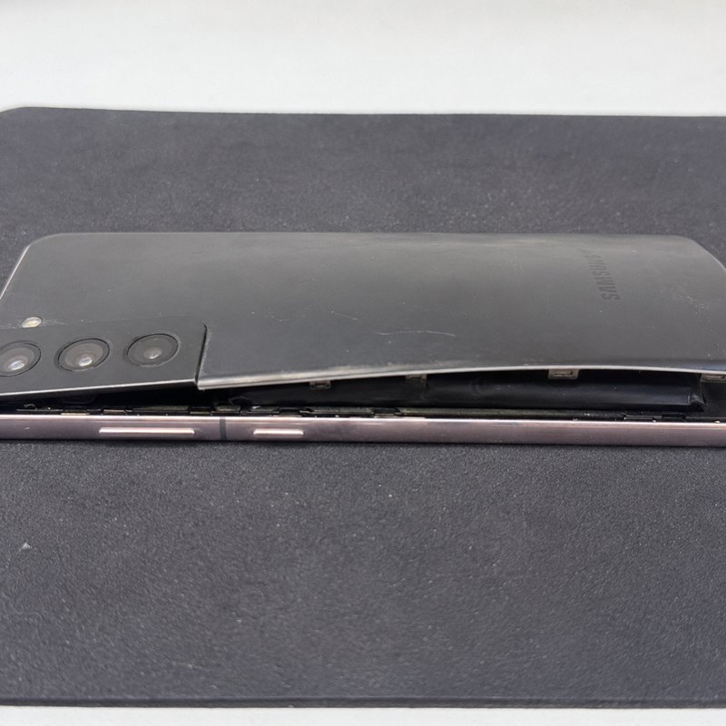 Samsung Galaxy S21 with the back panel lifted off the frame by a swollen battery