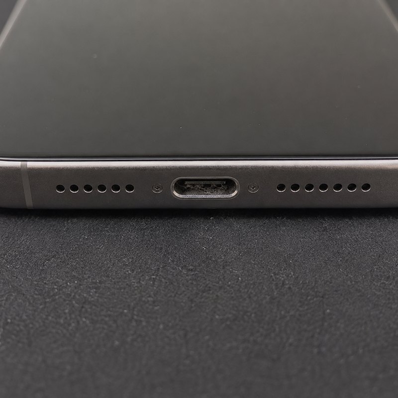 Close-up of a phone charging port packed with compacted pocket lint